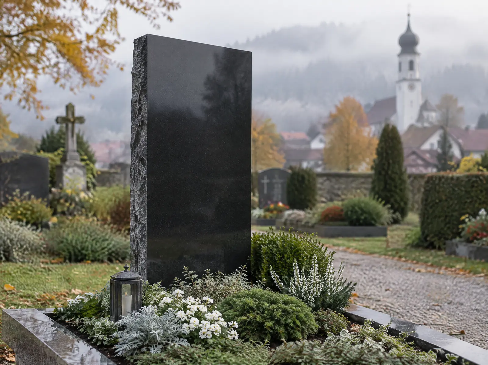 Stele aus poliertem schwarzem Granit auf einem gepflegten Grab, im Hintergrund eine Dorfkirche im Nebel